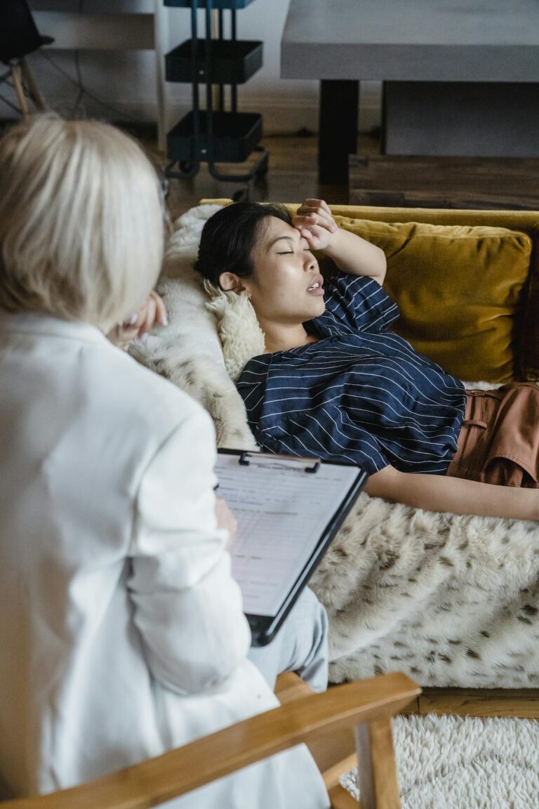 Woman in therapy session with psychologist, expressing emotions, lying on couch.